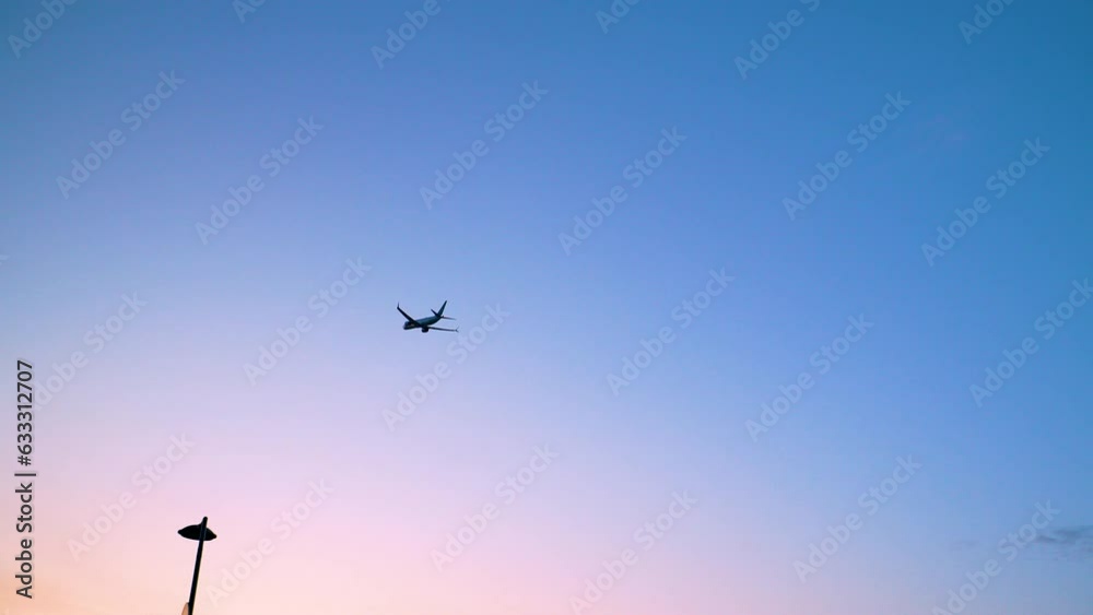 Silhouette Of An Airplane Flying Against Blue Sky - low angle Silhouette Of An Airplane Flying Against Blue Sky - low angle