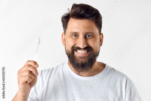 Perfect smile. Bearded mature man holding toothbrush against white studio background. Dental hygiene, oral care. Concept of men's beauty, skin care, cosmetology, health and wellness. Copy space for ad