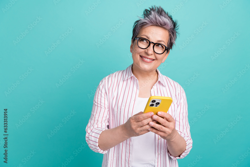 Photo of minded pensioner business woman holding new smartphone look empty space interested planning isolated on cyan color background