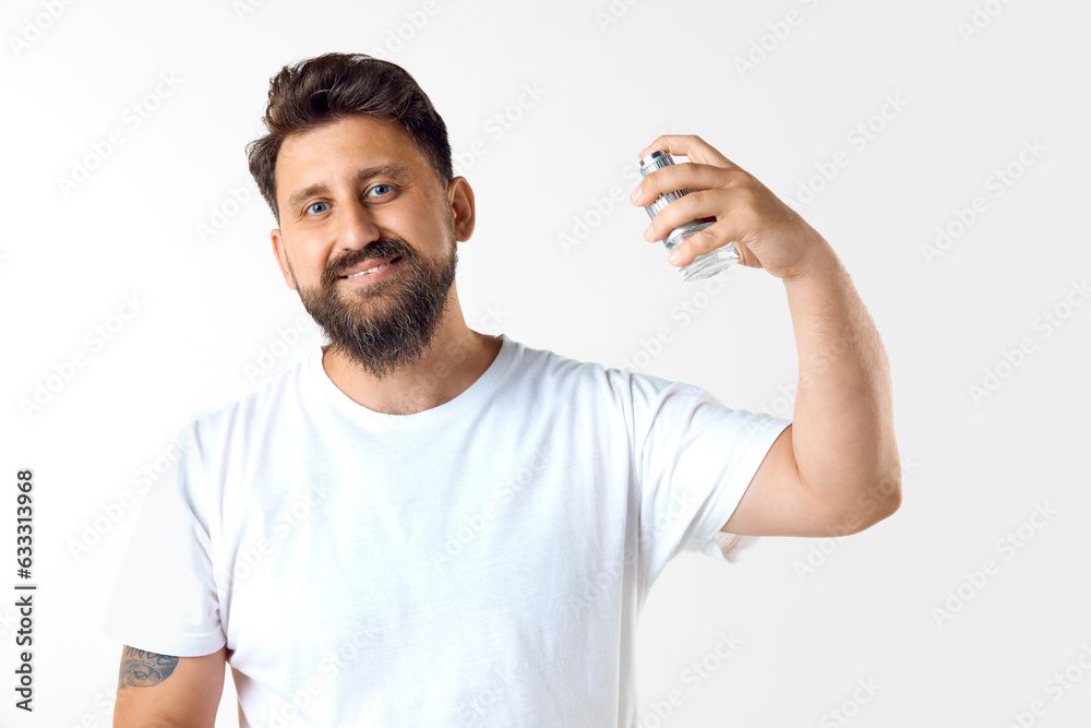 Handsome, mature, bearded man in white t-shirt applying perfume against white studio background. Concept of men's beauty, skin care, cosmetology, health and wellness. Copy space for ad Handsome, mature, bearded man in white t-shirt applying perfume against white studio background. Concept of men's beauty, skin care, cosmetology, health and wellness. Copy space for ad