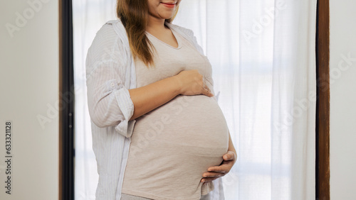 Free Download pregnancy woman hugging her tummy and feel happy with big belly at window - GFXLoad