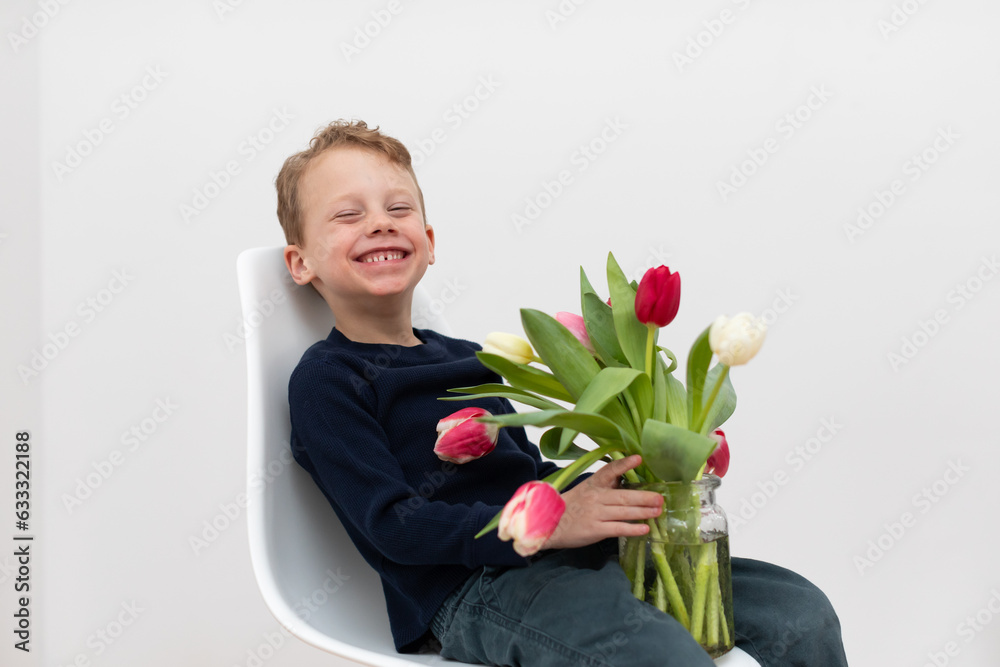 A charming young boy with his tulips bouquet in a white background. A charming young boy with his tulips bouquet in a white background.