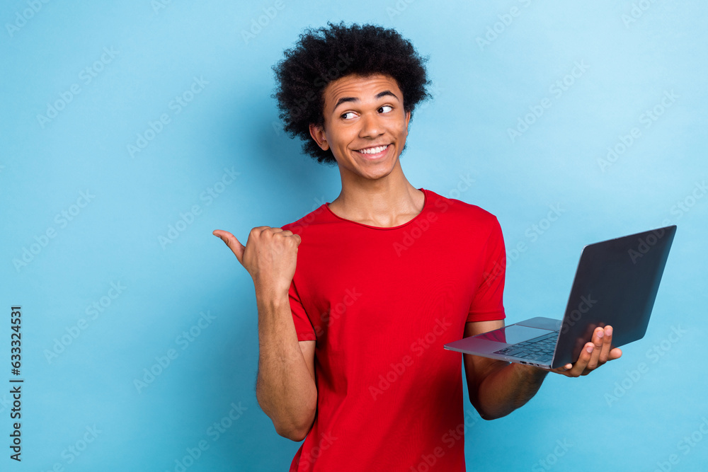 Photo of nice handsome person hold wireless netbook look indicate finger empty space isolated on blue color background Photo of nice handsome person hold wireless netbook look indicate finger empty space isolated on blue color background