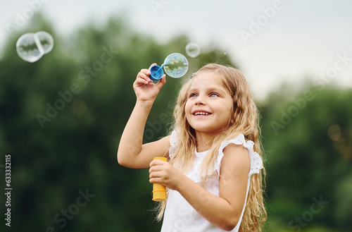 Little girl is playing with bubbles outdoors