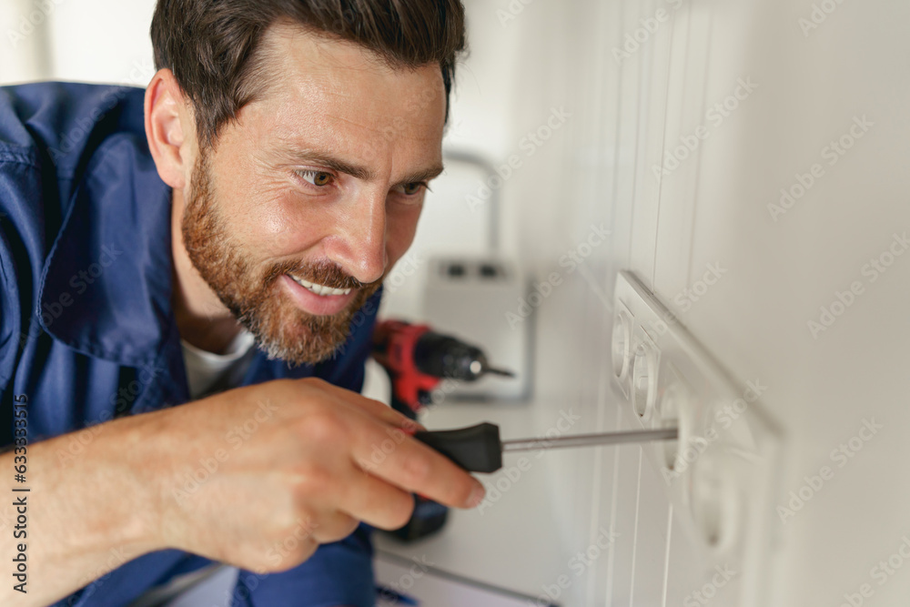 Close up of electrician using screwdriver while installing new electrical socket on home kitchen