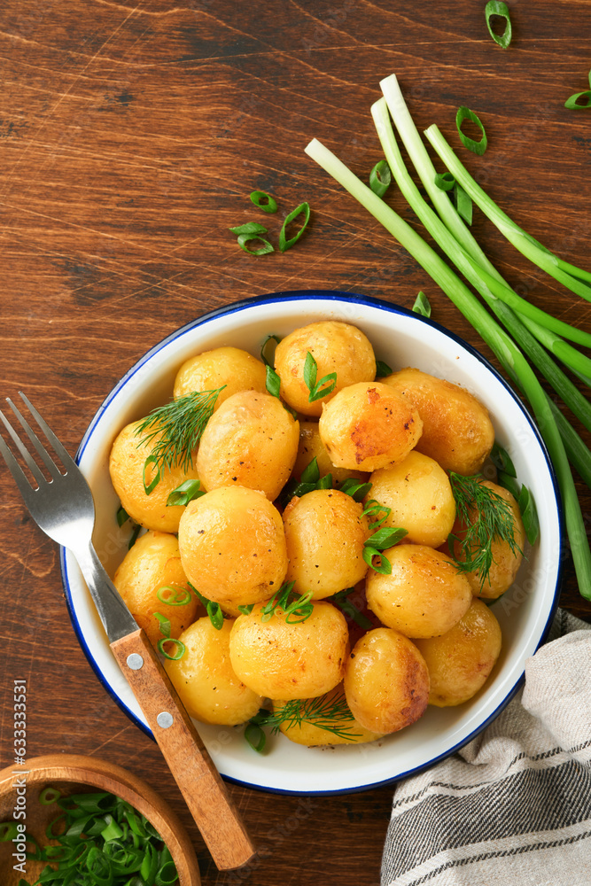 Boiled new or young potatoes with butter, fresh dill and onions in white bowl on dark old rustic wooden background. Tasty new boiled potatoes. Top view. Boiled new or young potatoes with butter, fresh dill and onions in white bowl on dark old rustic wooden background. Tasty new boiled potatoes. Top view.