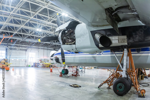 Transport turboprop airplane in the hangar. Aircraft under maintenance. Checking mechanical systems for flight operations