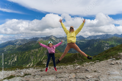 Mother and daughter are jumping in the Tatra Mountains in Zakopane on a summer day. photo