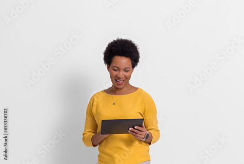 Smiling young female freelancer with afro hairstyle working over digital tablet on white background