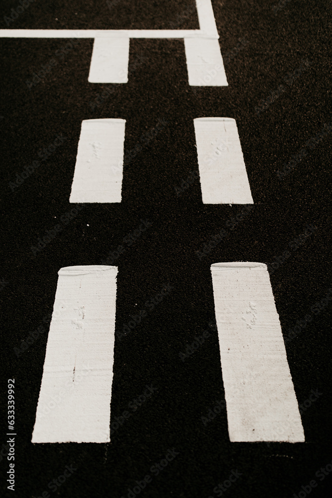 Dark asphalt road background with white marking lines. Close up photo. 
