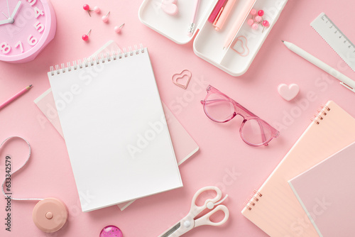 Back-to-school must-haves. Top view of essential school supplies: pens, ruler, notebook, tape measure, pushpins and more on pastel pink surface. Perfect for educational advertisements or messages