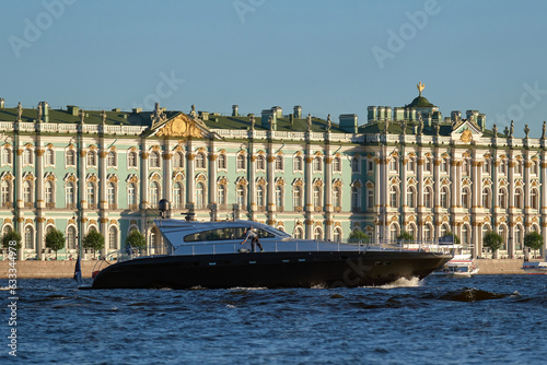 A black speedboat floats along the river, next to the embankment of a European city. Rent of boats and motor yachts.