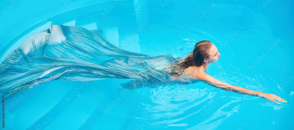 A beautiful young girl is swimming in bessein. Summer vacation and resort. Gray clothing covers the body and floats beautifully on the surface .