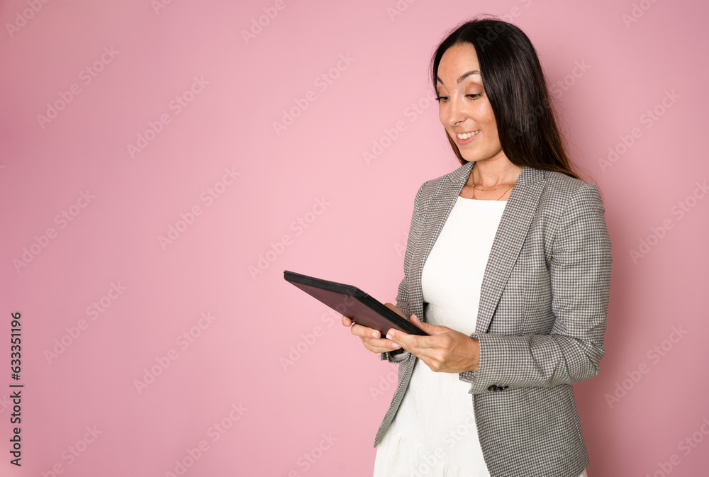 Portrait of cheerful charming girl hold tablet toothy smile empty space isolated on pink color background Portrait of cheerful charming girl hold tablet toothy smile empty space isolated on pink color background