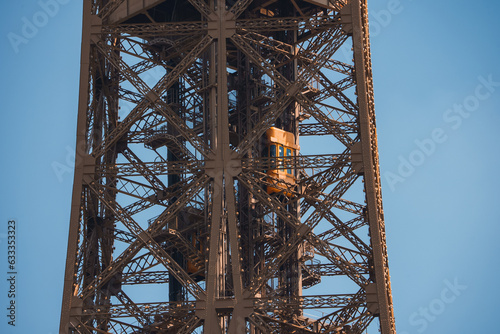 Close up view of the Eiffel Tower in Paris, France with a clear blue sky and green landscape.
