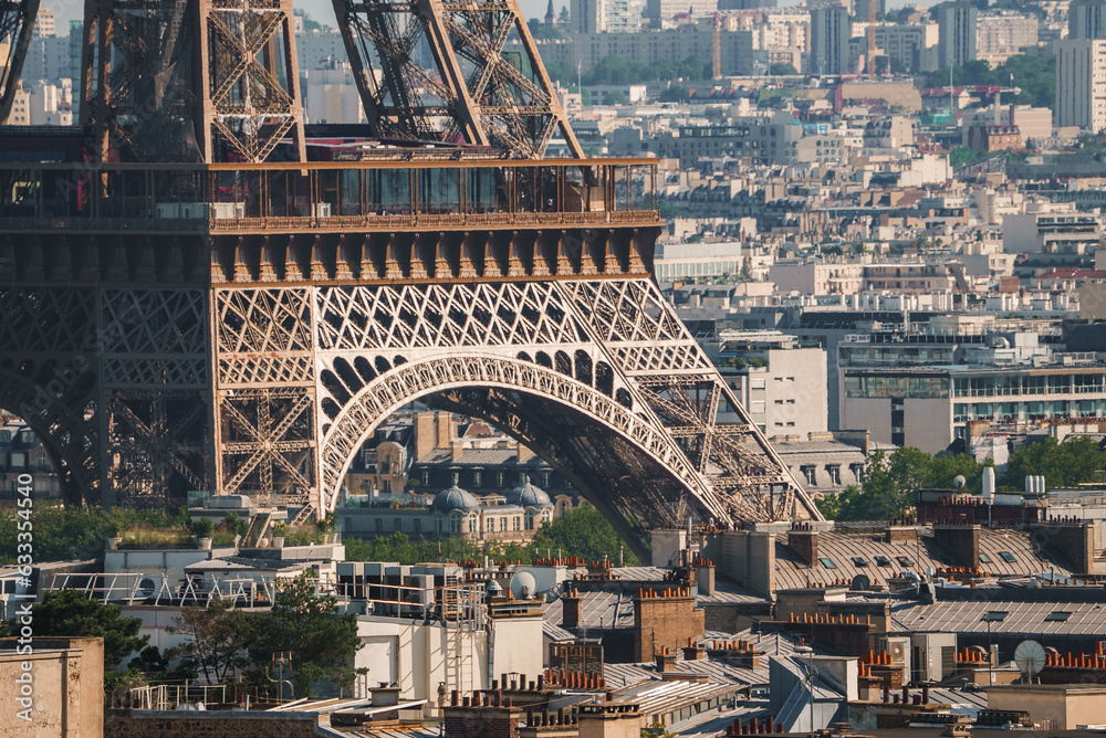 Fototapeta premium Daytime shot of the bronze Eiffel Tower in Paris, France under a hazy blue sky with city landscape.