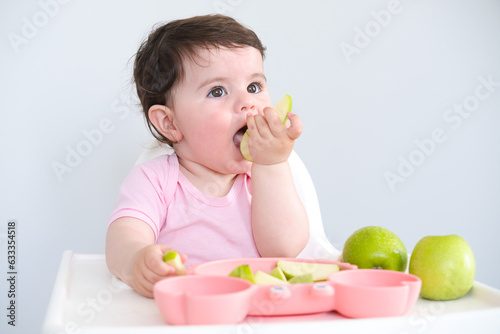 baby eating apple sitting in a high chair. weaning photo