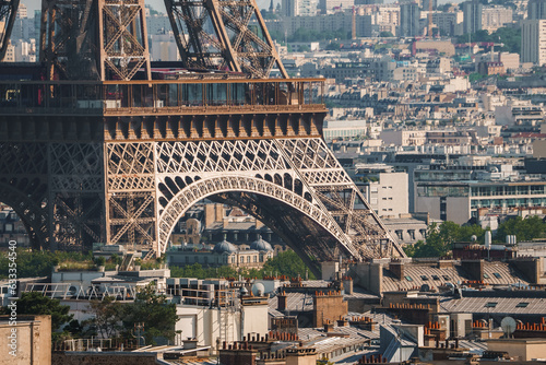 Daytime shot of the bronze Eiffel Tower in Paris, France under a hazy blue sky with city landscape.
