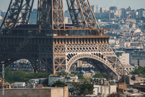 Close up view of the Eiffel Tower in Paris, France with a clear blue sky and green landscape. © Aerial Film Studio