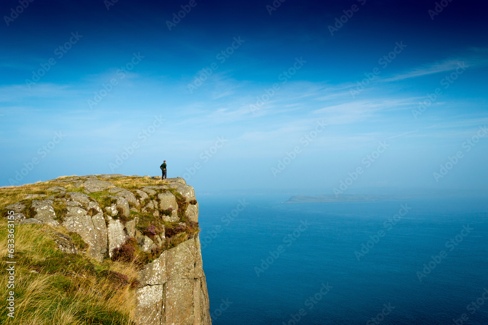 A  solo hiker on the high cliffs of Fair Head in County Antrim in Northern Ireland 