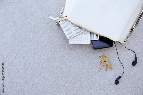 White handbag open with pills and women's accessories.