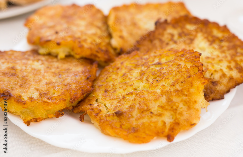 Fried grated potato pancakes with sour cream on white plate Fried grated potato pancakes with sour cream on white plate
