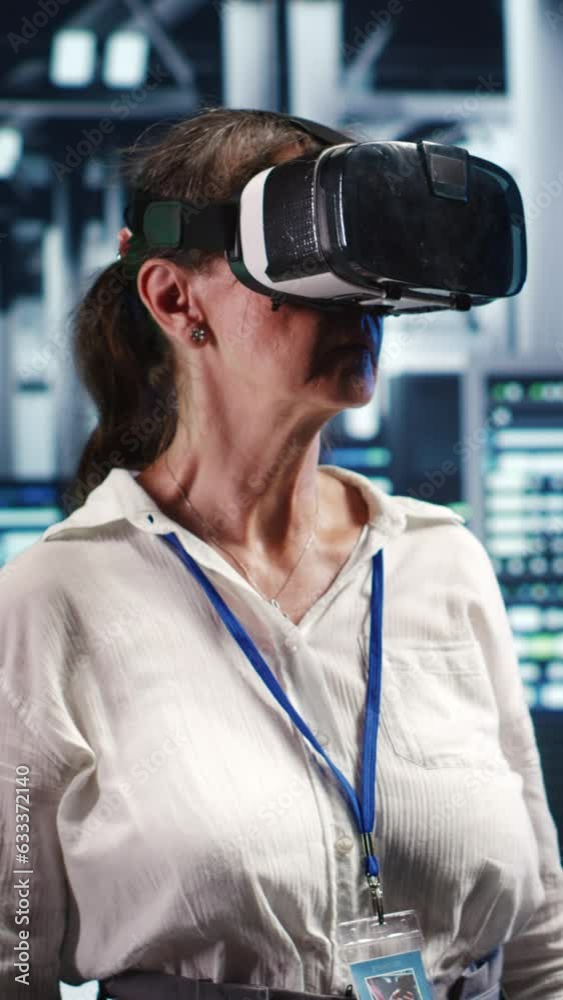 Vertical video Older computer scientist in modern server hub wearing virtual reality headset, performing racks maintenance. Licensed professional using vr glasses in high tech workplace to do checkup Vertical video Older computer scientist in modern server hub wearing virtual reality headset, performing racks maintenance. Licensed professional using vr glasses in high tech workplace to do checkup