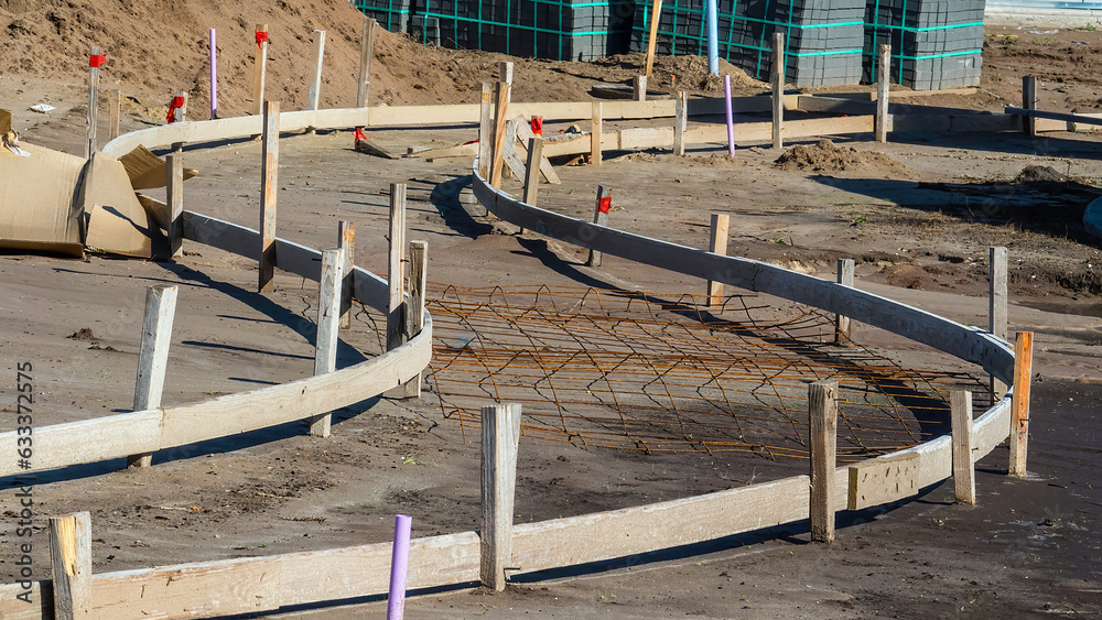 Curved hardboard forms with wooden stakes in place for pouring of