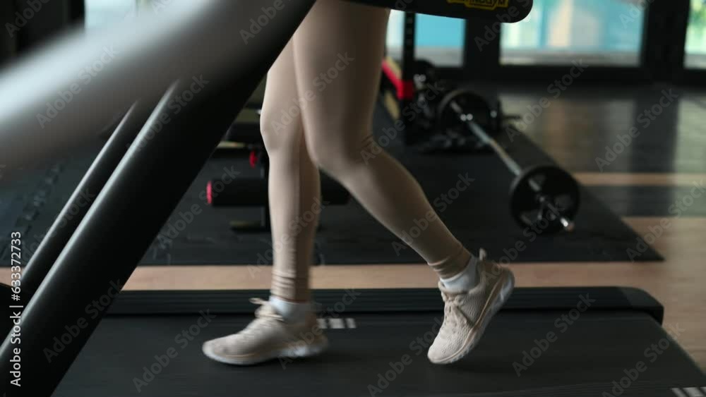 Legs of unrecognisable woman running on the treadmill in the fitness studio Legs of unrecognisable woman running on the treadmill in the fitness studio