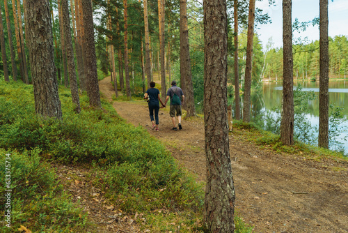 senior couple holding hands walking in forest along lakeside