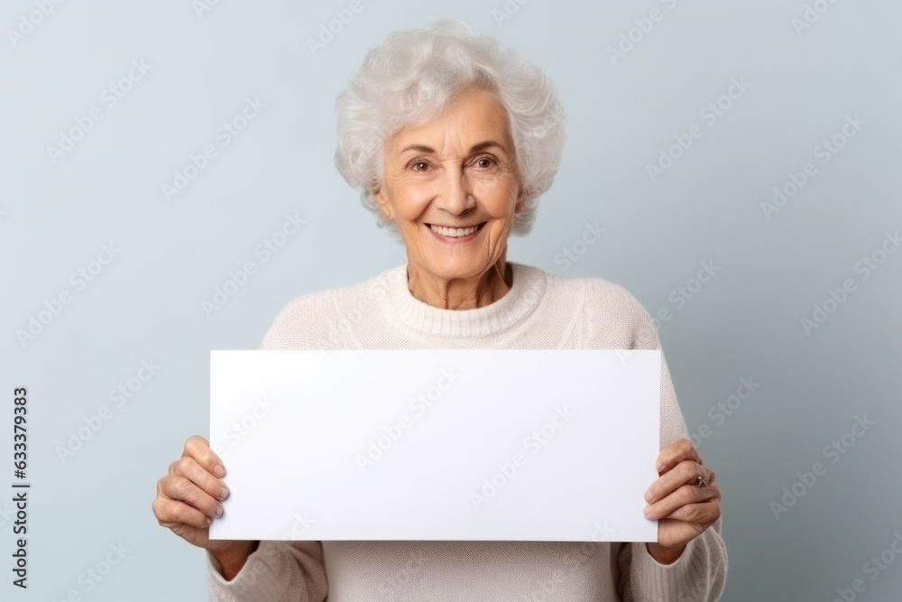 Happy old woman holding blank white banner sign, isolated studio portrait. Happy old woman holding blank white banner sign, isolated studio portrait.