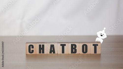 Business and technology concept. Wooden block with text and white robot. Chat bot with artificial intelligenc or Ai, Smart assitance communication. photo