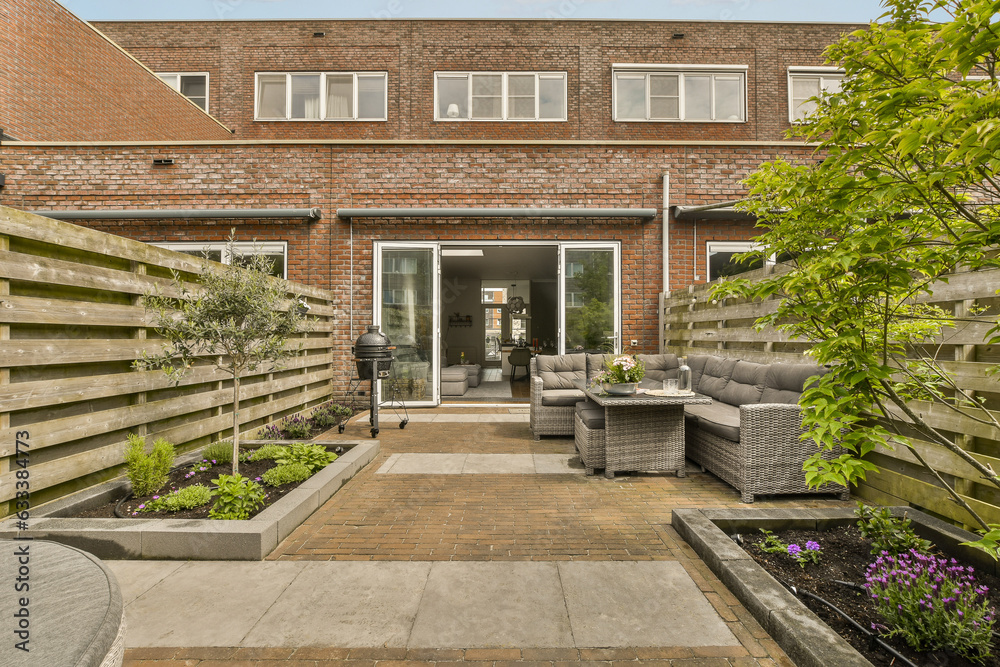 an outside area with furniture and plants in the middle of the yard, surrounded by a brick wall that has been painted red an outside area with furniture and plants in the middle of the yard, surrounded by a brick wall that has been painted red