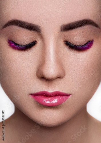 Beautiful close-up shot of female with long false lashes. Young woman with perfect natural make-up  pink eyelash extensions. Macro beauty photo of fashion colored volume lash extension set  full lips