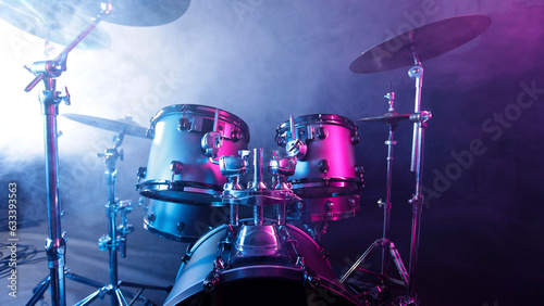 A drum set on a dark stage in the fog and neon lights.