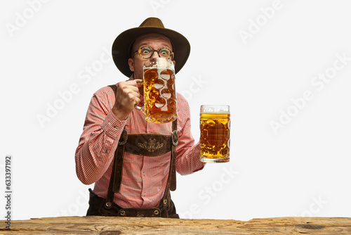 Photography Portrait of young cheerful man in hat, wearing folk Bavarian clothes, drinking beer isolated white background