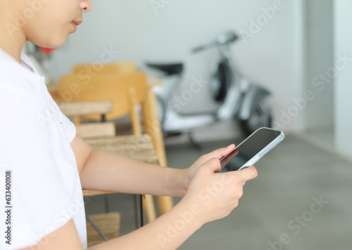 A woman sitting in a restaurant looks at the screen of her cell phone and reads a message. Woman hands with smartphone for online shopping and payment. Shopping service on online web. Spending money.