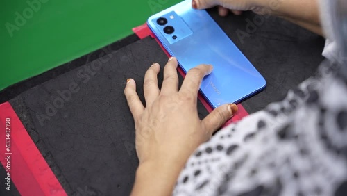 lady worker putting stickers on the back of a smartphone in smartphone production assembly line
