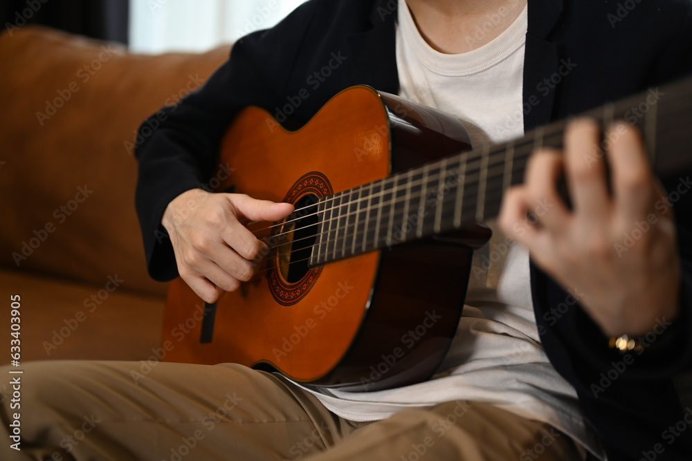 Fototapeta premium A man playing a guitar at home. Domestic life concept.