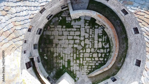 Aerial drone view of paved courtyard of round fortification called Fort de Ronce, Val Cenis, Savoie, Rhone Alpes, France. Bird eye view of old military fort in French Alps, overgrown with green grass photo