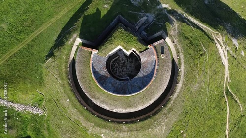 Aerial drone view of round fort called Fort de Ronce, Val Cenis, Savoie, Rhone Alpes, France. Bird eye panoramic view of old military fortification in French Alps, overgrown with bright green grass photo