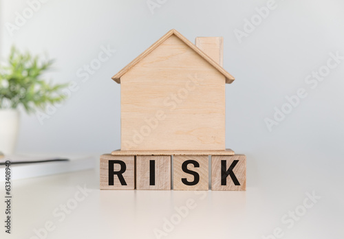 Risk text on wooden cube and wood Home. Crisis, autumn business, risk, economic downturn, developer, real estate and property concept