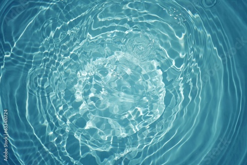 Blue water with ripples on the surface. Defocus blurred transparent blue colored clear calm water surface texture with splashes and bubbles. Water waves with shining pattern texture background.