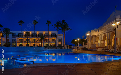 illuminated swimming pool in the courtyard of a mediterranean hotel at dusk