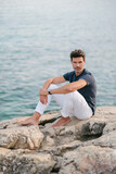Adult man meditating on rocky seashore
