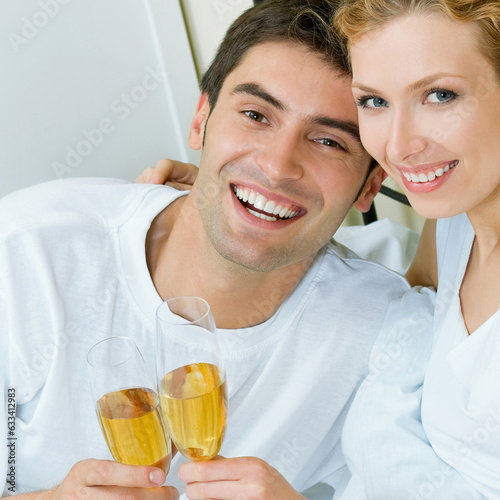 Portrait of cheerful smiling couple with champagne, indoors