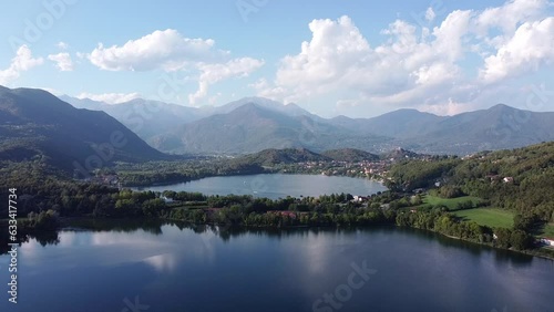 Aerial drone view of two lakes called Laghi di Avigliana. Lakes with calm water surrounded by mountain ranges in Italian Alps. Water surface reflects clouds, mountains in background, Piedmont, Italy photo