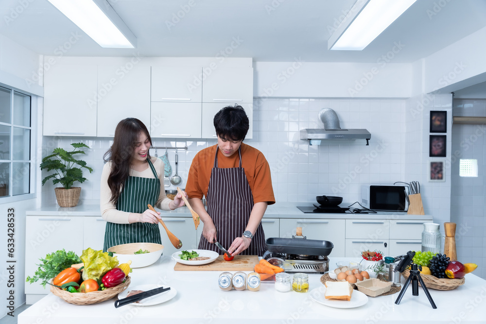 Happy portrait of loving young asian of having fun standing a cheerful preparing food and enjoy cook cooking with vegetables, meat, bread while standing on a kitchen Condo life or home Happy portrait of loving young asian of having fun standing a cheerful preparing food and enjoy cook cooking with vegetables, meat, bread while standing on a kitchen Condo life or home