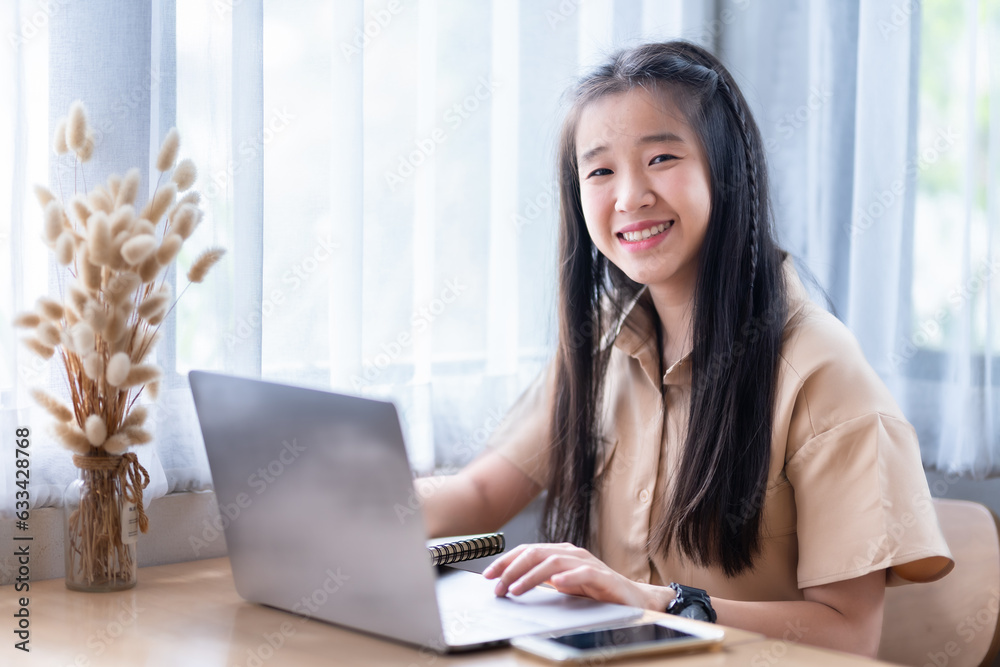 Happy of Young asian teen girl college student Taking written Notes to on notebook casual using laptop computer.Online education, elearning concept,freelance people businessfemale Happy of Young asian teen girl college student Taking written Notes to on notebook casual using laptop computer.Online education, elearning concept,freelance people businessfemale