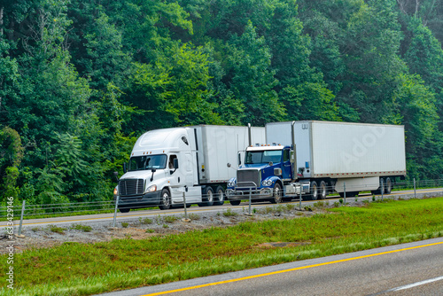 Two Eighteen-Wheelers Travel Down An Interstate Highway